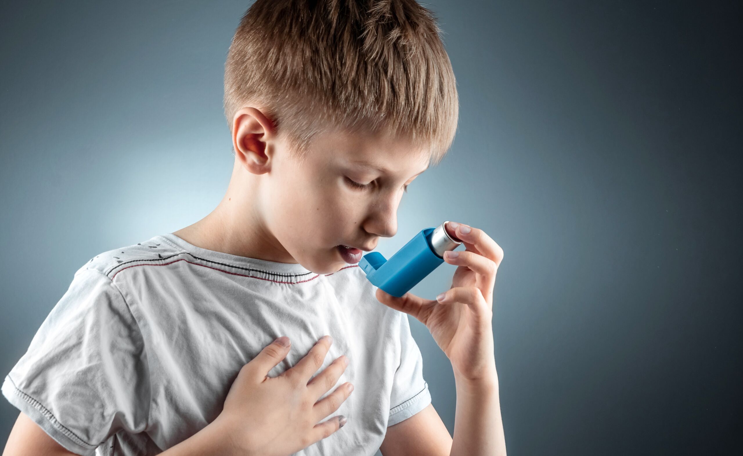 Portrait of a boy using an asthma inhaler to treat inflammatory diseases, shortness of breath. The concept of treatment for cough, allergies, respiratory tract disease