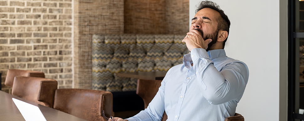 Служител в офиса, изпитващ умора, причинена от лошо качество на въздуха в офиса и ниска производителност